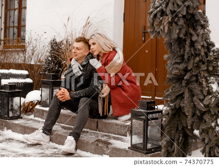 A loving couple in a gentle embrace. The guy kisses his girlfriend. Valentines day. Young guy hug his girlfriend in winter park. 74370775