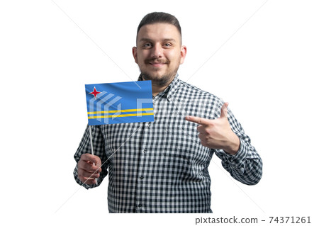 White guy holding a flag of Aruba and points the finger of the other hand at the flag isolated on a white background 74371261