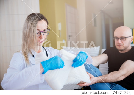 Female doctor helping a patient with a fractured leg. 74371794