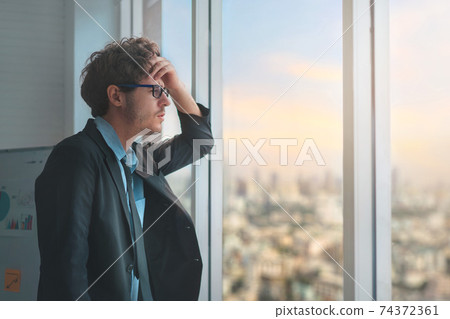 Sad unhappy businessman losing job and holding his forehead while having headache and look far out of the window Hopelessly , Business failure and laid off unemployment problem, Economic problem. Sad unhappy businessman losing job and holding his forehead while having headache and look far out of the window Hopelessly , Business failure and laid off unemployment problem, Economic problem. 74372361