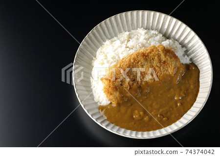 A black background shot of a cutlet curry with a large pork cutlet in the middle (overhead view) 74374042