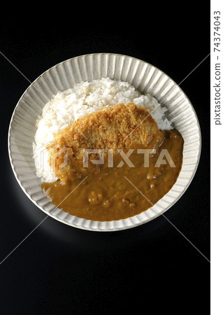 A black background shot of a cutlet curry with a large pork cutlet in the middle (overhead view) 74374043