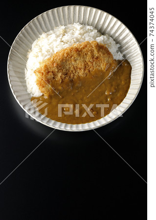 A black background shot of a cutlet curry with a large pork cutlet in the middle (overhead view) 74374045