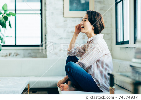 A middle-aged woman relaxing in the living room A middle-aged woman relaxing in the living room 74374937