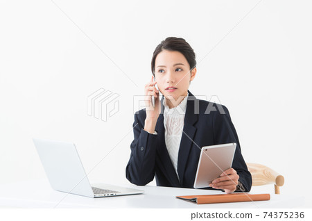 A busy-looking woman in her 20s doing desk work. A busy-looking woman in her 20s doing desk work. 74375236