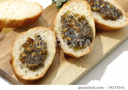 Apply olive oil with nuts on the carved French bread and eat (white background) 74375541