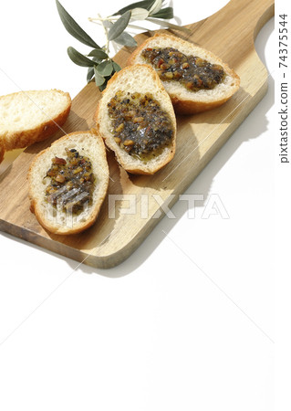 Apply olive oil with nuts on the carved French bread and eat (white background) 74375544