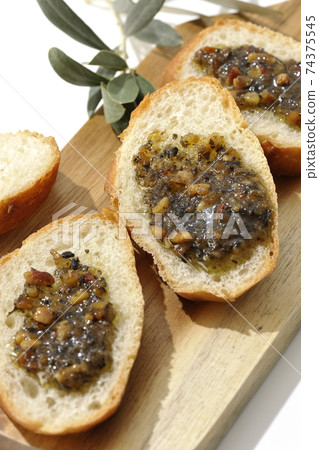 Apply olive oil with nuts on the carved French bread and eat (white background) 74375545