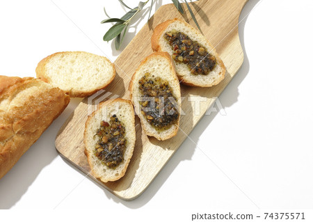 Apply olive oil with nuts on the carved French bread and eat (white background) 74375571