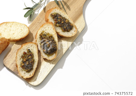 Apply olive oil with nuts on the carved French bread and eat (white background) 74375572