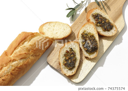 Apply olive oil with nuts on the carved French bread and eat (white background) 74375574