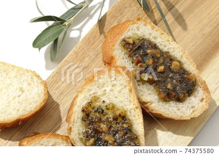 Apply olive oil with nuts on the carved French bread and eat (white background) 74375580