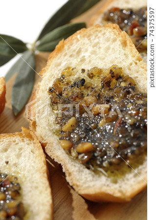 Apply olive oil with nuts on the carved French bread and eat (white background) 74375597