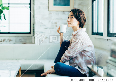 在客廳裡喝咖啡的中年女人 在客廳裡喝咖啡的中年女人 74375788