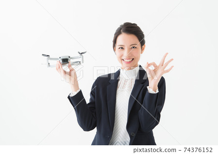 A woman holding a drone and making an OK sign. A woman holding a drone and making an OK sign. 74376152
