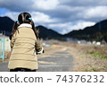 Back view of a girl standing on a road rich in nature 74376232