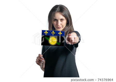 Happy young white woman holding flag of Guadeloupe and points forward in front of him isolated on a white background Happy young white woman holding flag of Guadeloupe and points forward in front of him isolated on a white background 74376964
