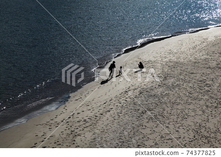三個父母和孩子在黃昏時沿著海灘散步的熱海陽光海灘剪影 74377825