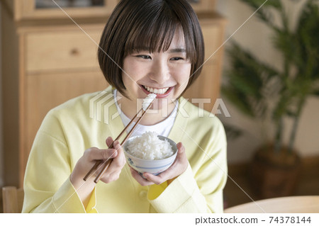 A young woman eating rice 74378144