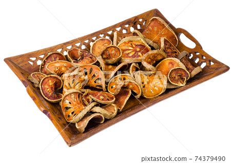 Wooden tray with dried bael fruit isolated on white background. Wooden tray with dried bael fruit isolated on white background. 74379490