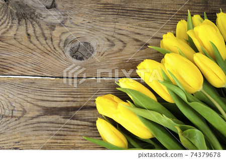 Yellow tulips lie on an old wooden surface Yellow tulips lie on an old wooden surface 74379678