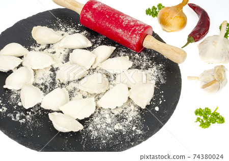Raw cooked homemade dumplings on black plate, spices. Raw cooked homemade dumplings on black plate, spices. 74380024
