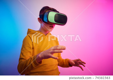 Boy with virtual reality glasses on colorful background. Future technology, VR concept 74381563