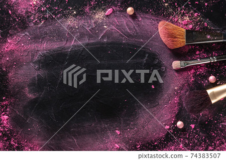 Makeup background with brushes, pearls, and crushed cosmetics 74383507
