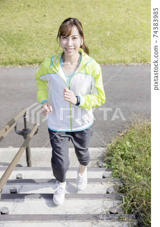 A young woman running up the stairs while running A young woman running up the stairs while running 74383985