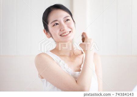 Women using antiperspirant sprays and perfumes 74384143