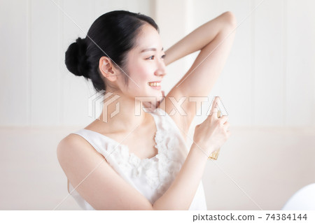 Women using antiperspirant sprays and perfumes 74384144