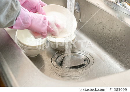 Wash the dishes with rubber gloves 74385099