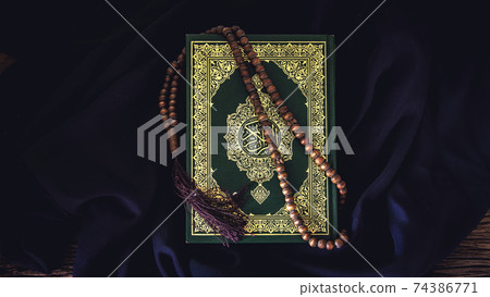 Koran - holy book of Muslims ( public item of all muslims ) on the table , still life . Koran - holy book of Muslims ( public item of all muslims ) on the table , still life . 74386771