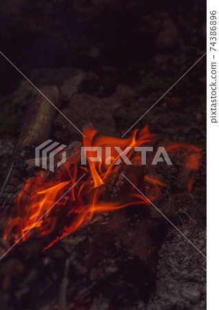 Blurred background. Small flame dying fire, bright red-orange flame. Cozy warm atmosphere by outdoors campfire recreation, burning wood. Blurred background. Small flame dying fire, bright red-orange flame. Cozy warm atmosphere by outdoors campfire recreation, burning wood. 74386896