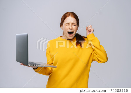 Successful happy shocked young woman with closed eyes holding laptop computer Successful happy shocked young woman with closed eyes holding laptop computer 74388316