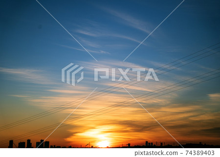 The golden sun appears on the horizon and makes the clouds shine orange 74389403