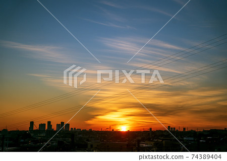 The golden sun appears on the horizon and makes the clouds shine orange 74389404