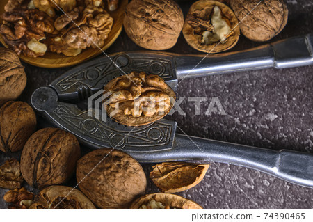 Vintage walnut cracker and walnuts on a dark texture background. Vintage walnut cracker and walnuts on a dark texture background. 74390465