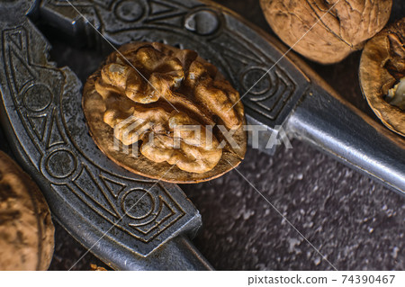 Vintage walnut cracker and walnuts on a dark texture background. Vintage walnut cracker and walnuts on a dark texture background. 74390467
