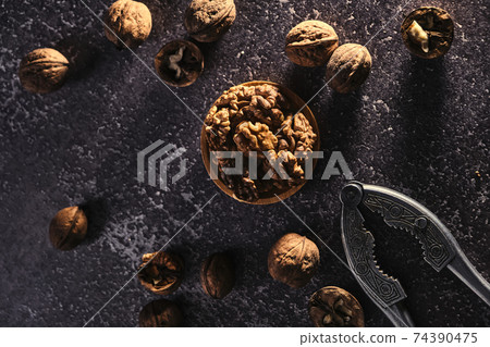 Vintage walnut cracker and walnuts on a dark texture background. Vintage walnut cracker and walnuts on a dark texture background. 74390475