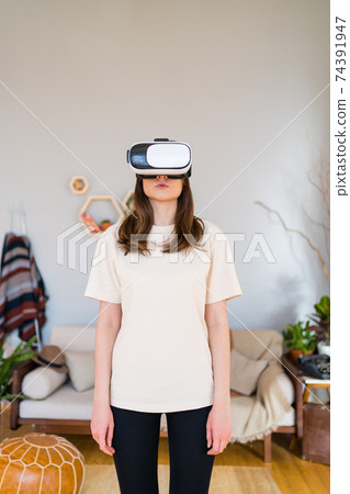 Woman in digital reality. VR Technology in cosy room Woman in digital reality. VR Technology in cosy room 74391947