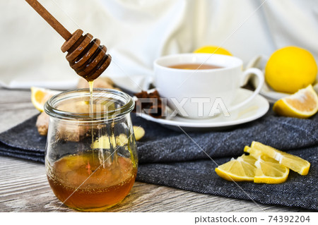 Ginger hot immunity boosting Vitamin natural drink With citrus, honey and ingredients in a rustic style on wooden background. Chamomile tea. Ginger hot immunity boosting Vitamin natural drink With citrus, honey and ingredients in a rustic style on wooden background. Chamomile tea. 74392204