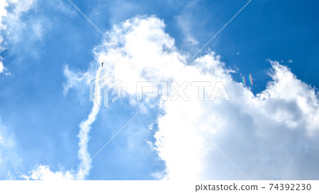 airplane doing acrobatics in blue sky leaves a smoke. Blue sky with airport contrail clouds. airplane doing acrobatics in blue sky leaves a smoke. Blue sky with airport contrail clouds. 74392230