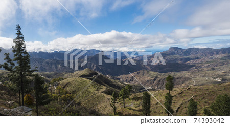 Panoramic view on mountains, Caldera and Barranco de Tejeda and Roque Bentayga rock from Cruz de Tejeda Viewpoint. Gran Canaria, Canary Islands, Spain Panoramic view on mountains, Caldera and Barranco de Tejeda and Roque Bentayga rock from Cruz de Tejeda Viewpoint. Gran Canaria, Canary Islands, Spain 74393042