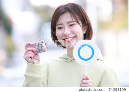 帶袖珍數碼相機和〇標籤的女性 74393199