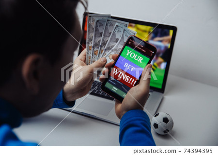 Lucky male winner at football betting with dollar money and phone in hands. Bet wins Lucky male winner at football betting with dollar money and phone in hands. Bet wins 74394395