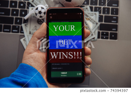 Lucky winner at football betting with phone in hand. Dollar bills and soccer ball on a keyboard. Betting online concept Lucky winner at football betting with phone in hand. Dollar bills and soccer ball on a keyboard. Betting online concept 74394397