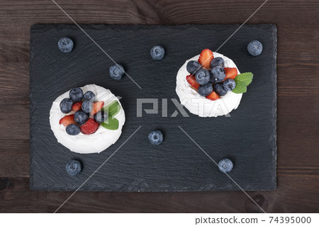 Cake Anna Pavlova. Airy meringue garnished with fresh strawberries and blueberries. Cake Anna Pavlova. Airy meringue garnished with fresh strawberries and blueberries. 74395000