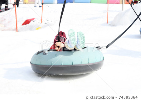 Girl playing with playground equipment in the snow Girl playing with playground equipment in the snow 74395364