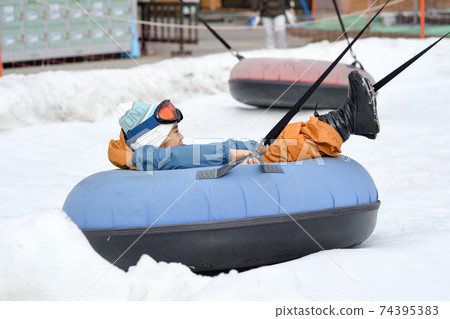 Girl playing with playground equipment in the snow 74395383